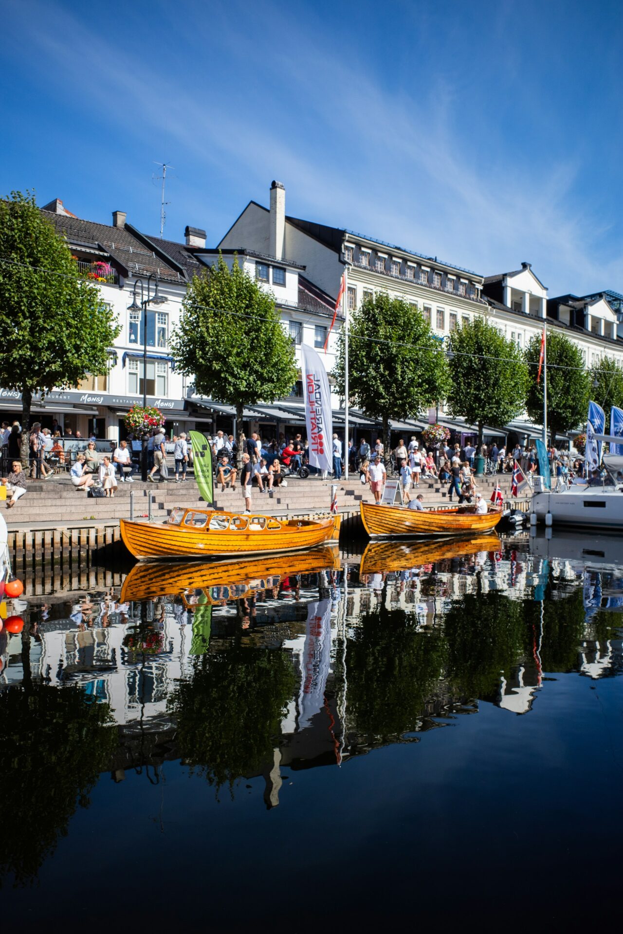 Arendal, pollen med tor trebåter og boder langs promenaden.